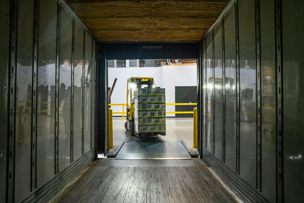 Forklift unloading palletized cargo from a trailer at a warehouse dock